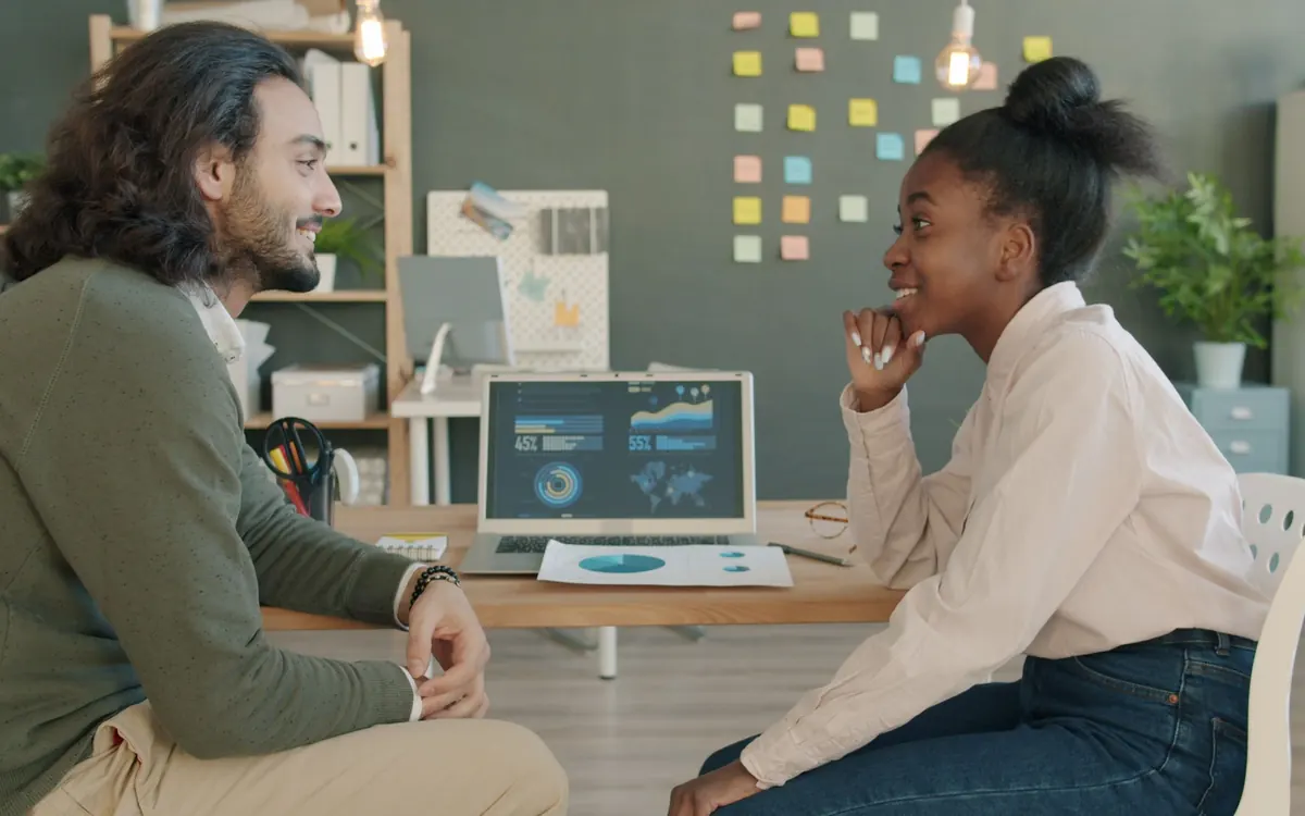 Two colleagues talking through a dashboard on a laptop