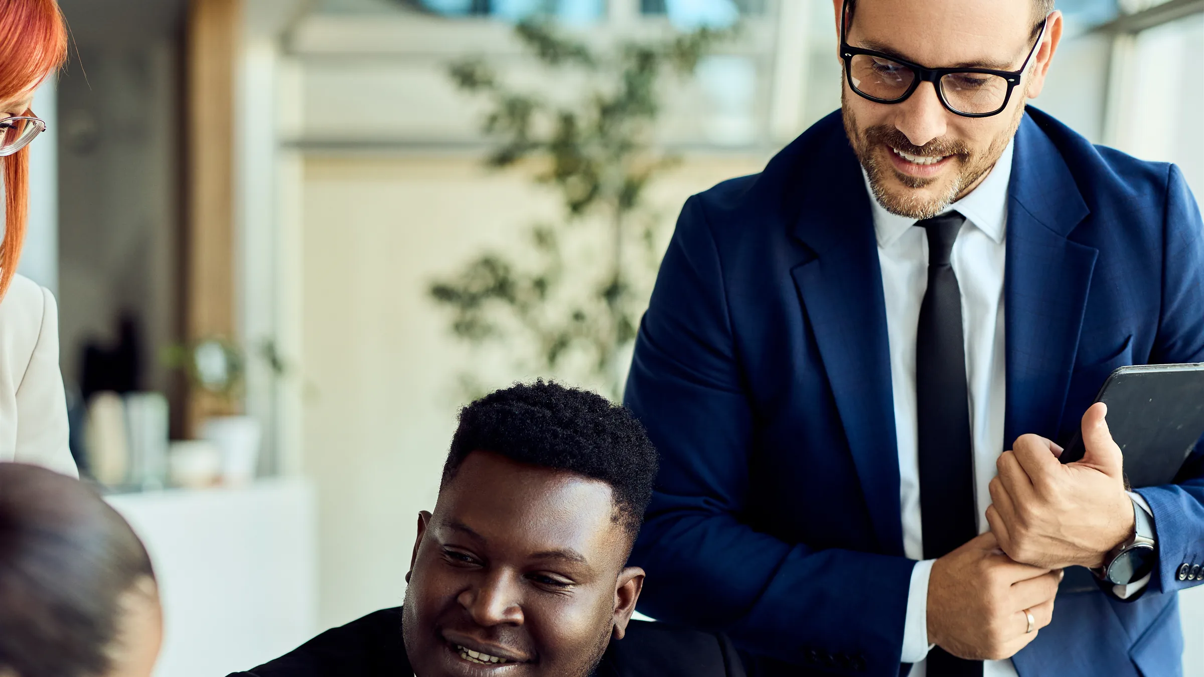 Colleagues review charts together at a laptop in a bright office