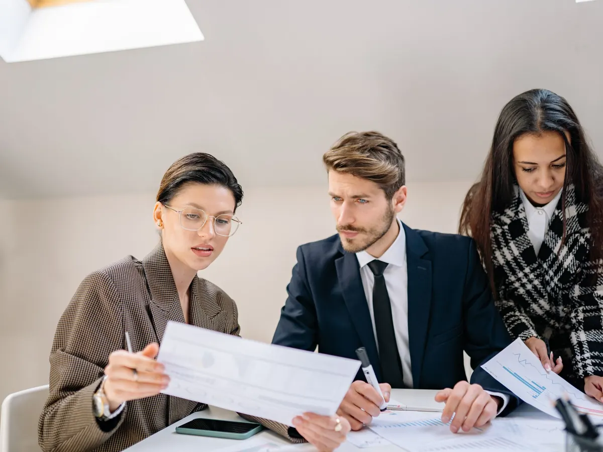 Three colleagues reviewing printed reports at a table