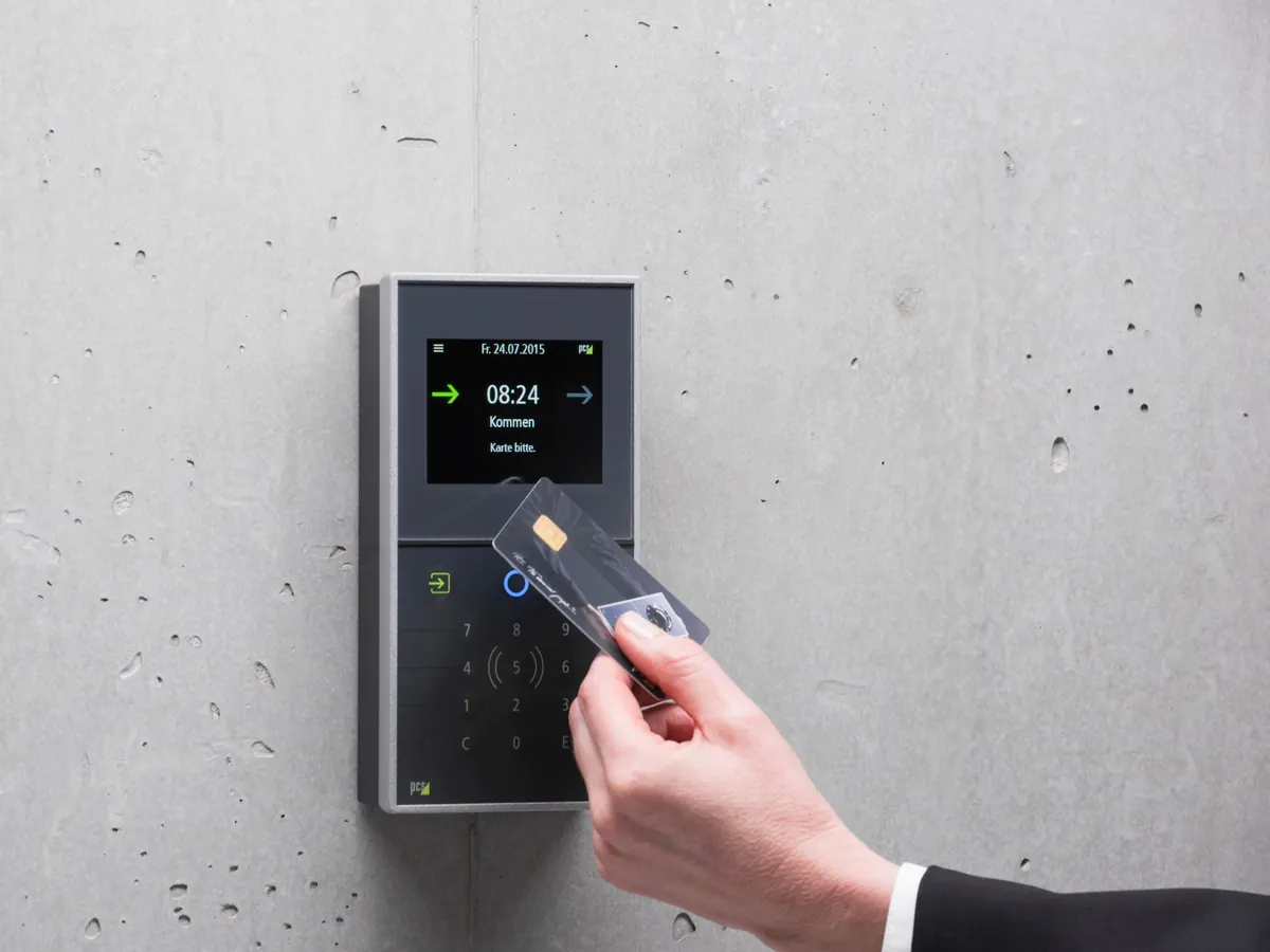 A hand holding an access card to a door reader