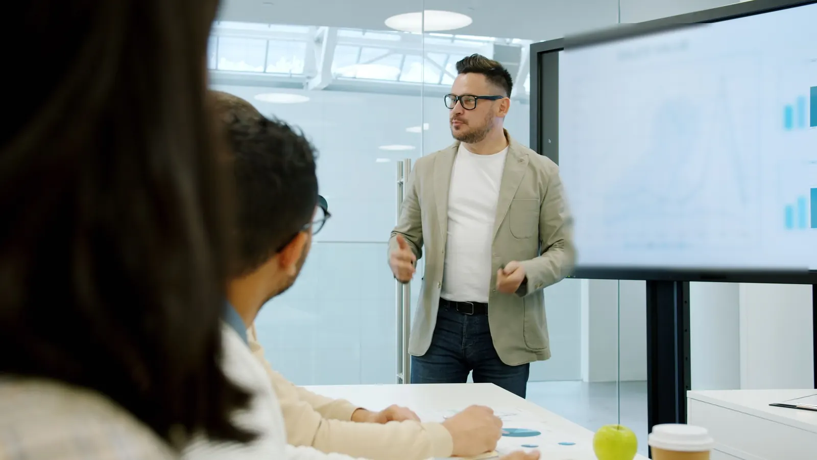 A consultant presents a sales chart to a client team in a meeting room