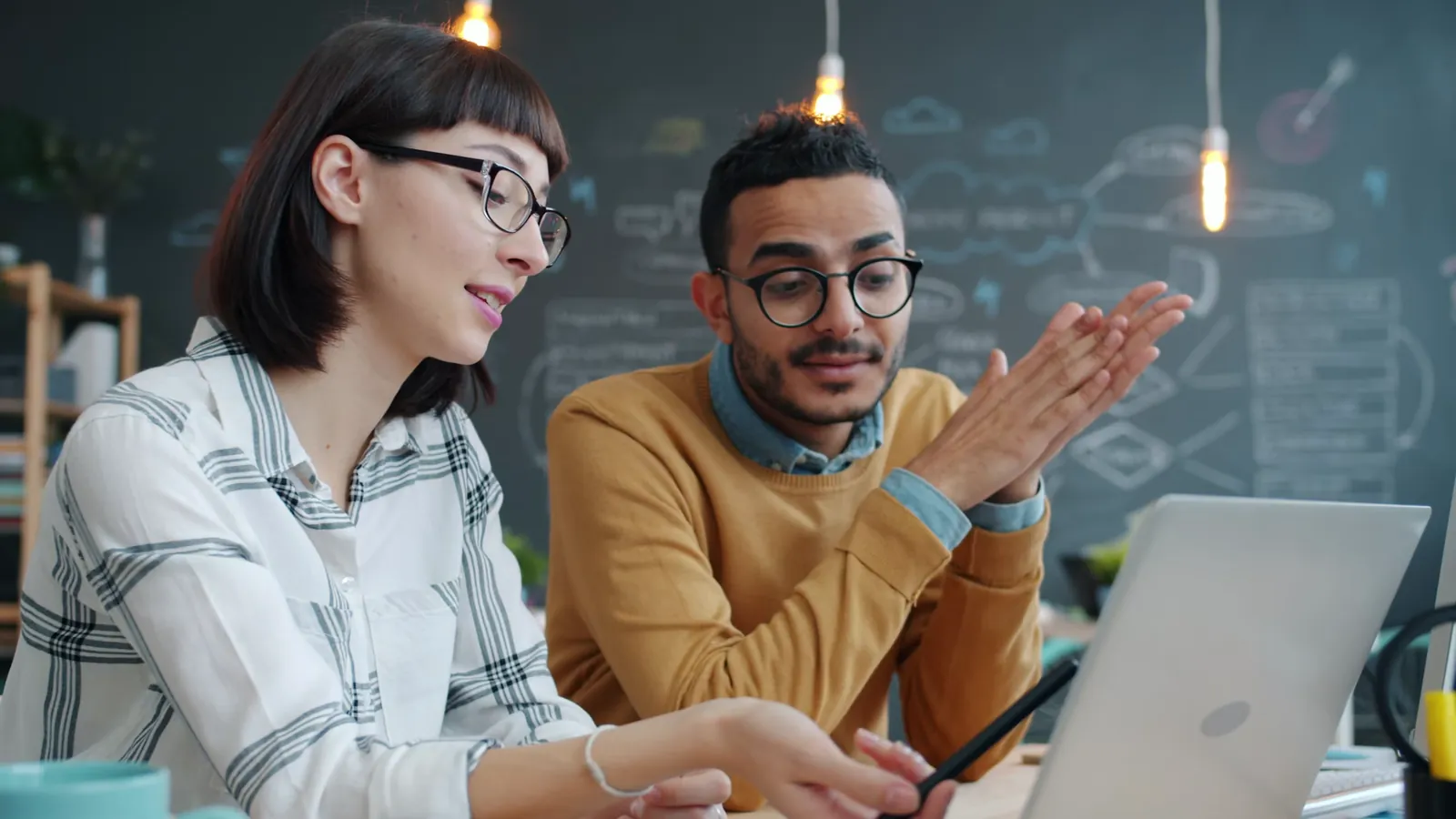 Two colleagues talk through an idea at a laptop