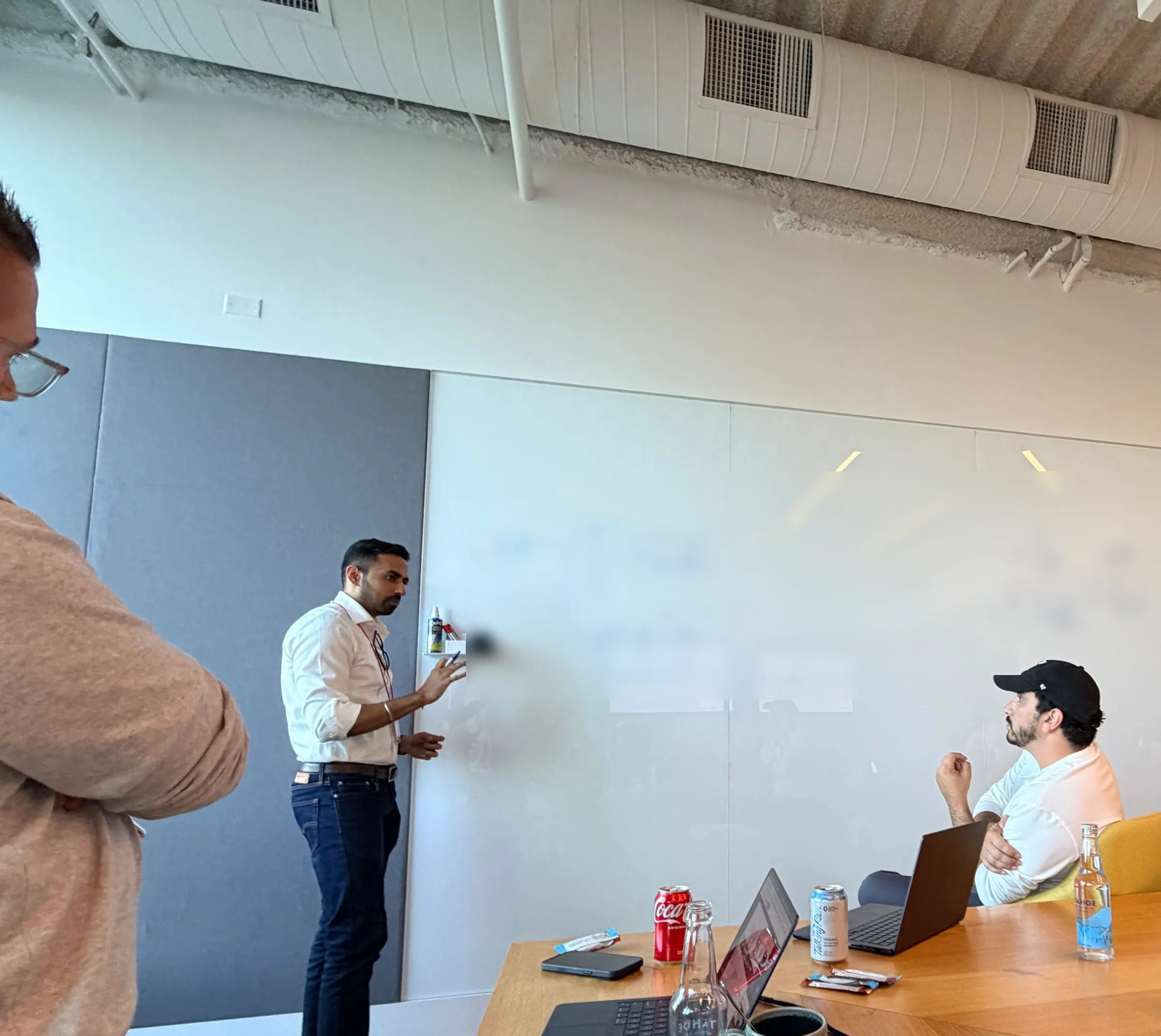 A CWX team member walks a working session through a plan at a whiteboard while the team listens